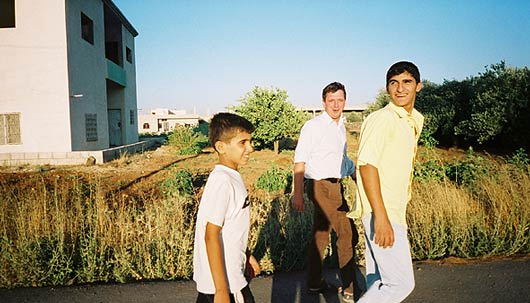 Mohammed, John and Yusuf stride in evening sunlight in the village